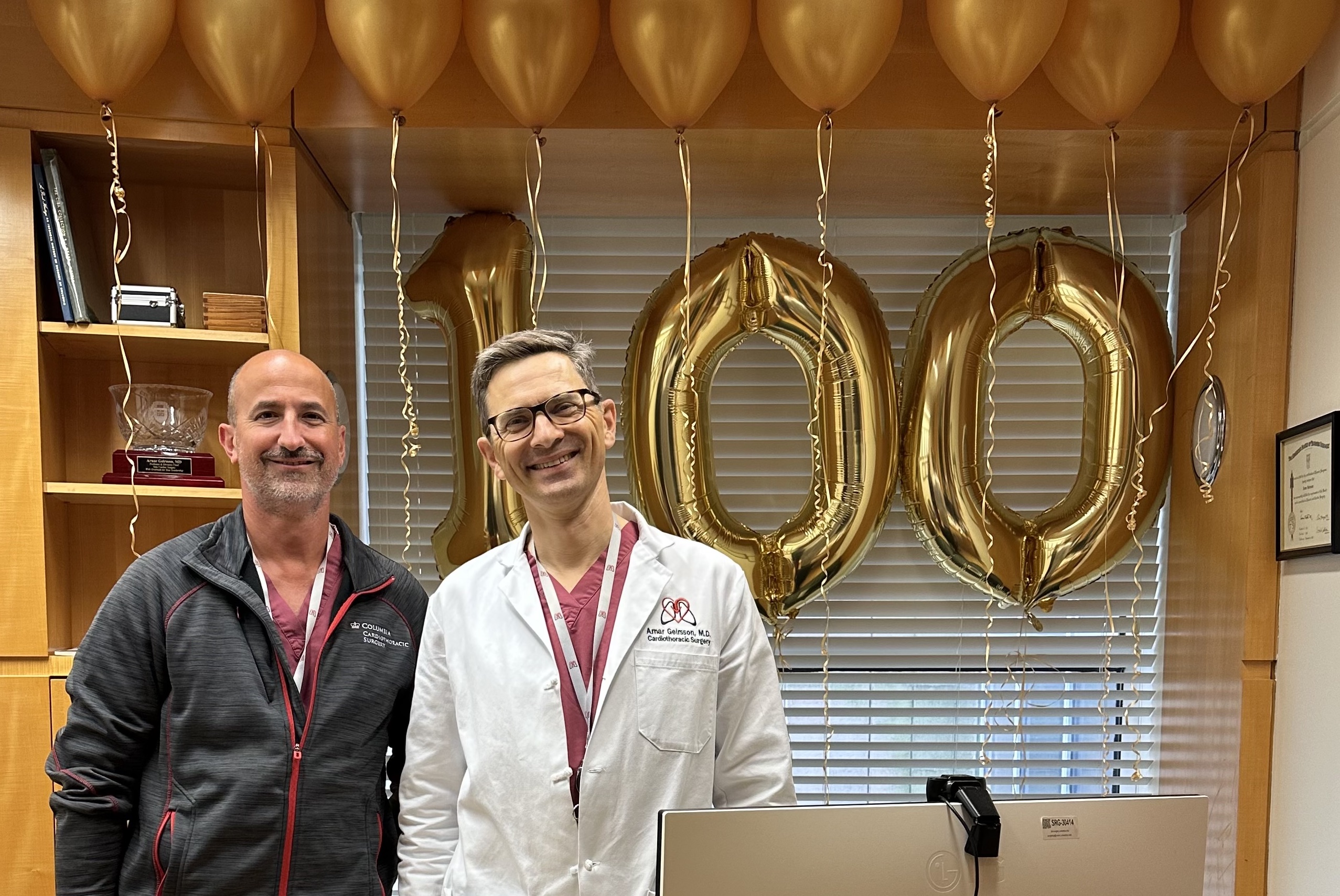 Surgeon and PA stand in front of balloons to celebrate 100th robotic heart surgery