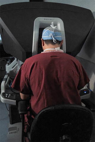 Photograph of surgeon seated at a Davinci robotic surgical system performing a minimally invasive operation.